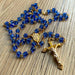 Blue rosary with gold accents on a wooden surface