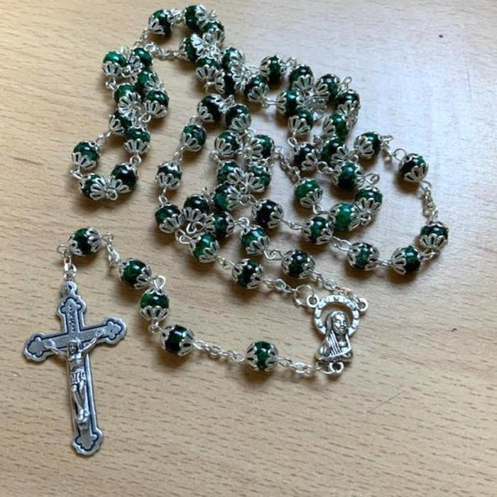 Green rosary with silver cross and medal on a wooden surface