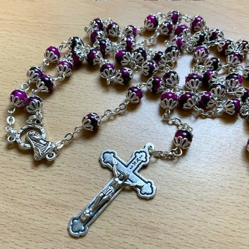 Rosary with purple beads and silver cross on a wooden surface