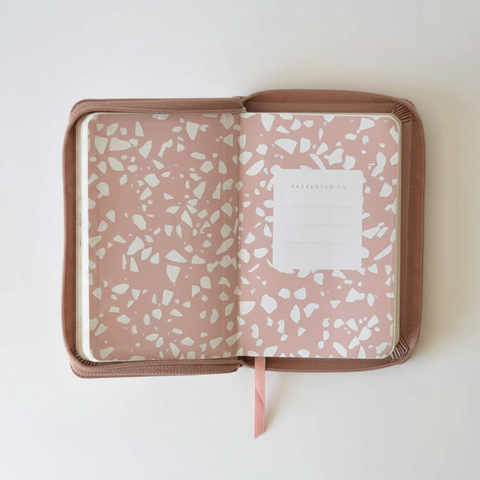 An open zippered notebook or planner cover in a terrazzo pattern, featuring a dusty pink background with white chips and a brown border, shown on a plain white background.