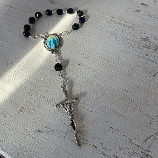 Rosary with black beads and a cross on a textured surface