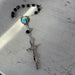 Rosary with black beads and a cross on a textured surface