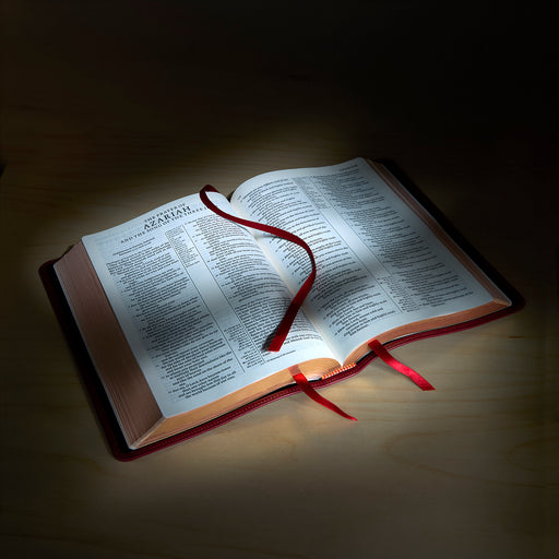 Open book with a red ribbon marker on a dark background