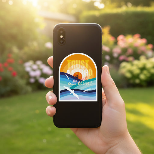 Arched sticker or print featuring a stylized seascape with blue and teal waves, white seagulls, a small sailboat, and the text 'TRUST IN THE LORD at all times' over an orange and yellow sun.