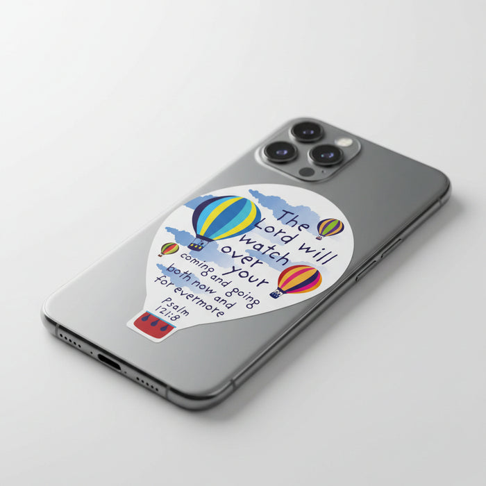 A die-cut sticker or decal shaped like a hot air balloon, featuring the Bible verse Psalm 121:8 ('The Lord will watch over your coming and going both now and for evermore') in dark blue lettering, alongside illustrations of colorful striped hot air balloons and blue clouds on a white background.