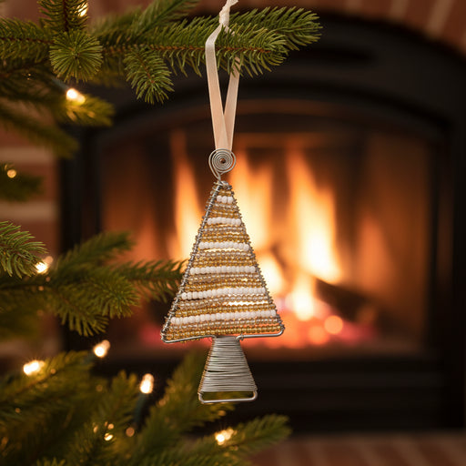 A handmade Christmas tree ornament made of silver and gold seed beads wrapped in silver wire, hanging from a white ribbon on a white background.