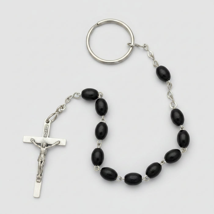 Black beaded rosary with a silver crucifix on a brown textured surface