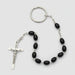 Black beaded rosary with a silver crucifix on a brown textured surface