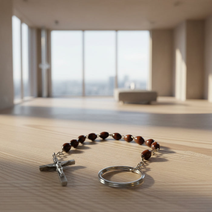 Brown beaded rosary with silver crucifix and key ring on a wooden surface
