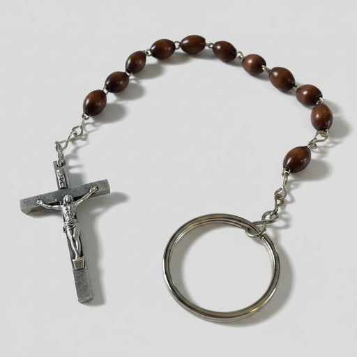 Brown beaded rosary with silver crucifix and key ring on a wooden surface