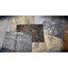 A decorative rectangular card or small booklet with an ornate multicolor floral and star pattern lies on top of several vintage-style illustrated cards showing maps and historical scenes, arranged on a rustic wooden surface.