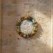 Decorative plate with a central relief of a mother and child surrounded by colorful fruit and flowers.
