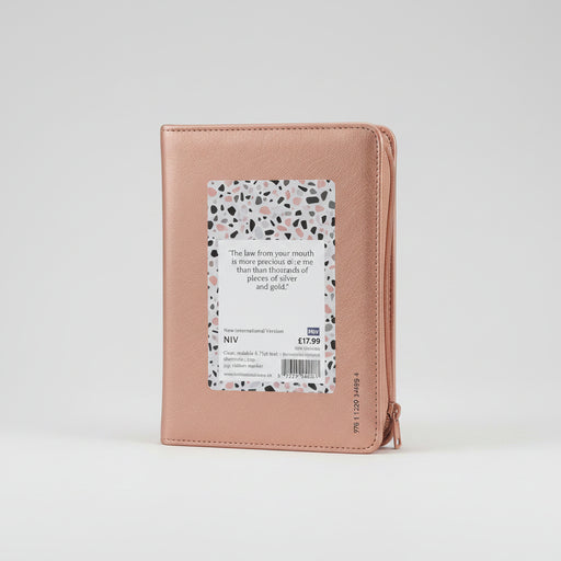A rose gold leather-bound Bible with a terrazzo-patterned paper insert on the back cover, photographed against a clean white background.