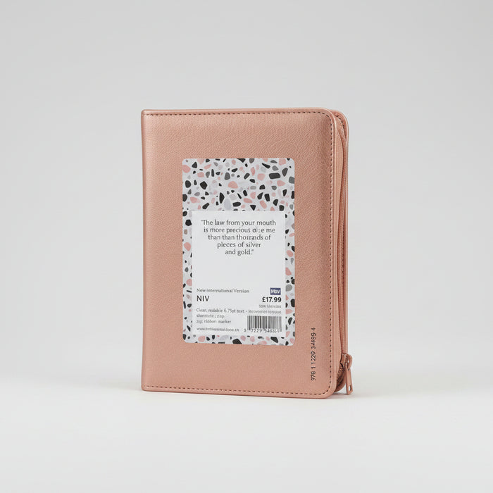 A rose gold leather-bound Bible with a terrazzo-patterned paper insert on the back cover, photographed against a clean white background.