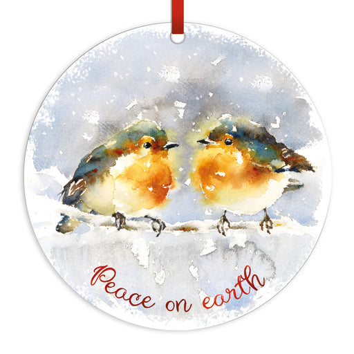 Round hanging ornament with a watercolor painting of two robin birds on a snowy branch and the words 'Peace on earth' in red script. A red hanging ribbon is visible at the top against a plain white background.