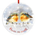 Round hanging ornament with a watercolor painting of two robin birds on a snowy branch and the words 'Peace on earth' in red script. A red hanging ribbon is visible at the top against a plain white background.