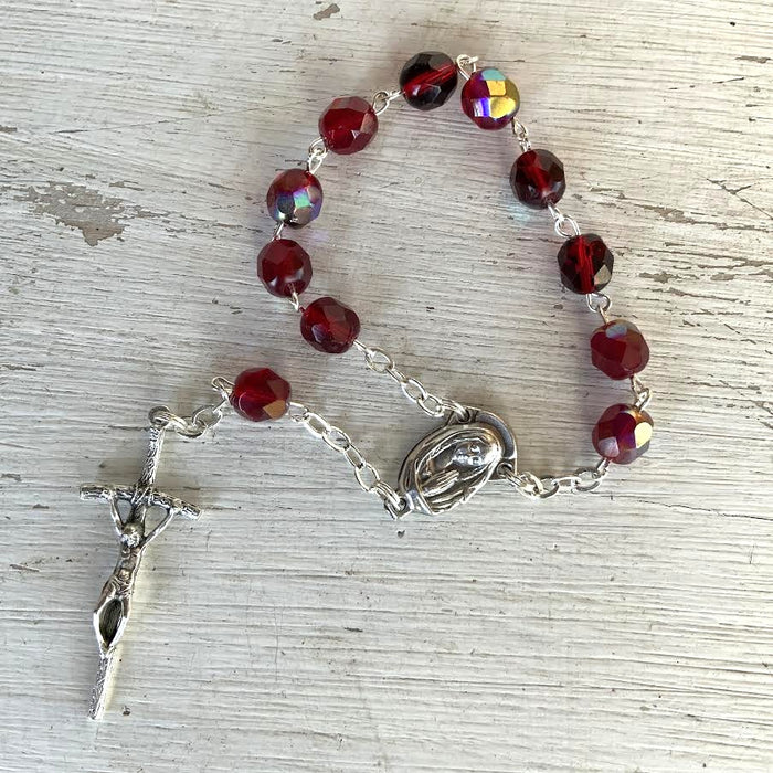 Rosary with red beads and silver accents on a textured surface